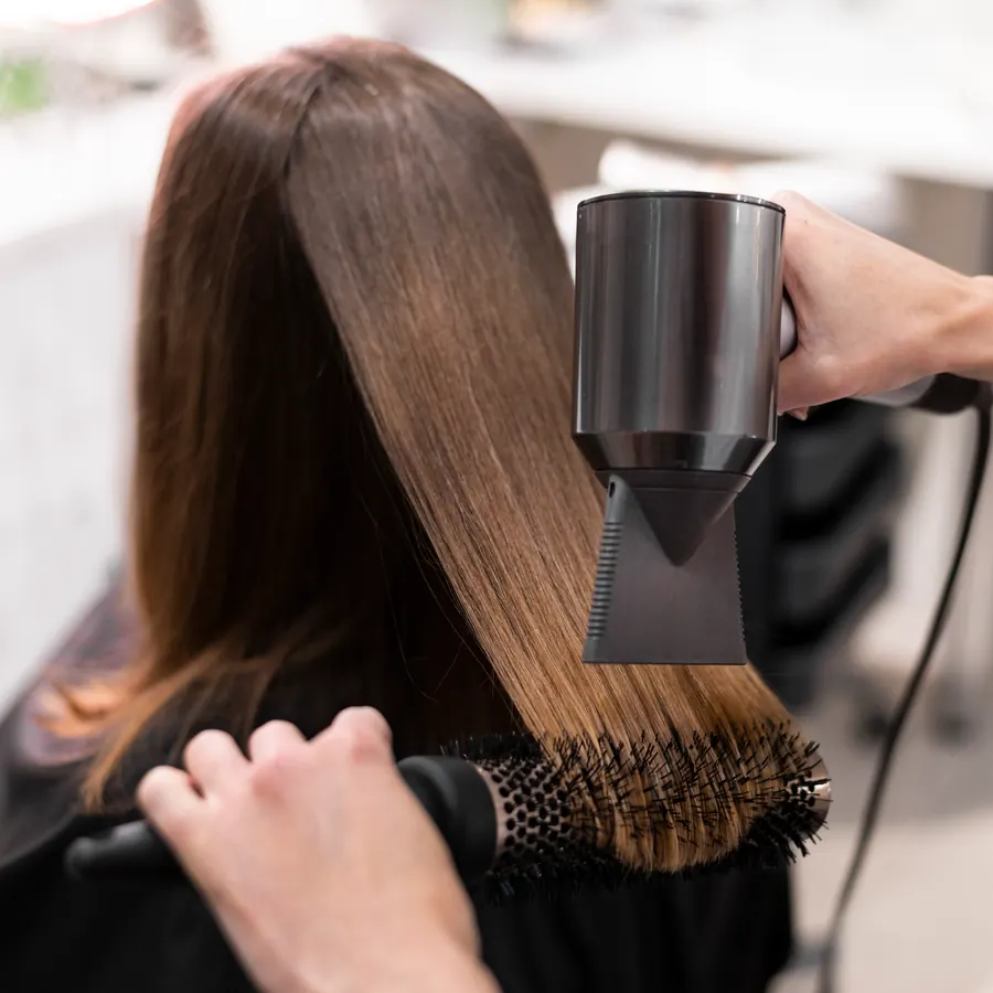 Piega con la spazzola tonda e il phon sui capelli castani lisci